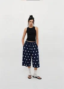 Female model wearing navy blue polka dot wide-leg cropped pants and black tank top
