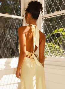 Detail of sexy backless satin maxi dress with halter neck and bow ties in pale yellow.