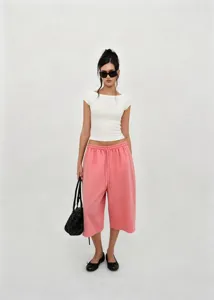 Fashion model wearing pink drawstring wide-leg shorts with a white t-shirt in studio
