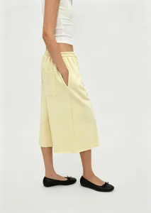 Side view of a woman wearing loose yellow culottes with black ballet flats for summer