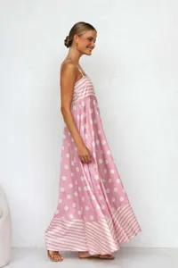 Elegant side profile of a pink polka dot and striped summer maxi dress on a model