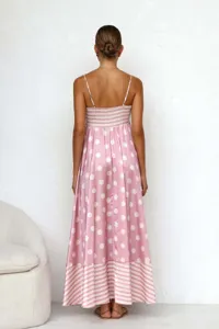 Back view of a chic pink polka dot maxi dress with striped hem detail and open back design