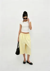 Full body shot of model wearing pale yellow wide-leg culottes with drawstring waist