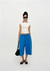 Full view of women's blue drawstring wide-leg pants paired with a white crop top
