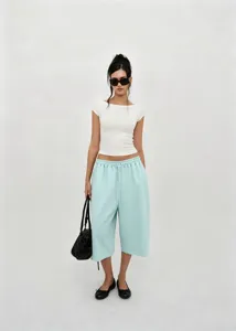 Detail view of model styling light blue retro wide-leg culottes in a minimalist setting.