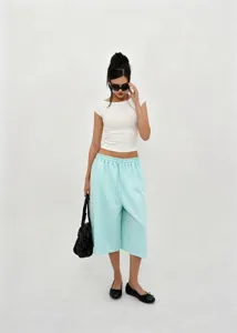 Full-body shot of a model wearing mint green wide-leg culottes and a white crop top.