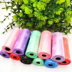Colorful dog waste bags rolls with cute paw print patterns for pet waste cleanup outdoors.