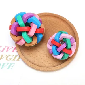 Close-up of colorful braided pet chew balls on wooden plate, showing vibrant woven texture.