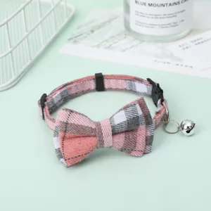 Detailed view of the pink plaid bow and silver bell on the adjustable pet collar.