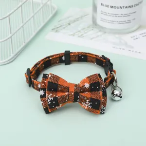 Detailed view of an orange and black plaid pet collar with a decorative bow and bell.