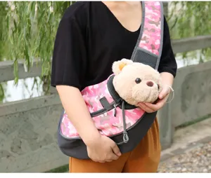 Detailed view of a pink camouflage pet sling carrier worn by a person in an outdoor setting