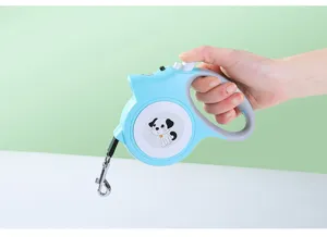Gros plan d'une laisse rétractable bleue avec lumière LED tenue à la main sur fond vert
