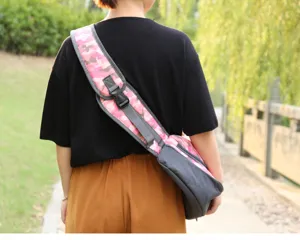 Back view of pink camouflage pet sling bag worn by a model in an outdoor setting