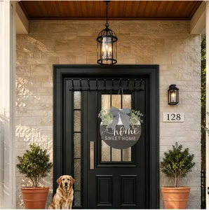 Elegant round wooden home sweet home sign hanging on a black door with eucalyptus leaves