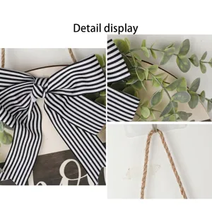 Close-up detail of the black and white striped bow and greenery on the wooden door hanger