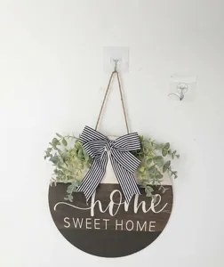 Close-up of a rustic wooden door sign featuring eucalyptus leaves and a striped bow