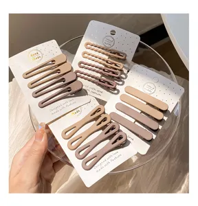 Matte hair clip detail view, featuring nude and mauve minimalist clips on display cards in bowl.