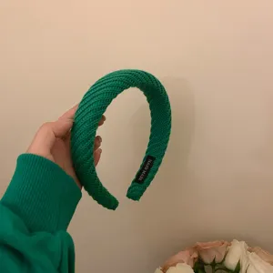 Detailfoto van groene gebreide haarband, brede gevlochten textuur, gezellig dagelijks accessoire.