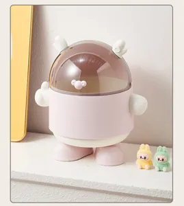 Détail d'une mini poubelle de bureau rose avec couvercle bombé sur une étagère