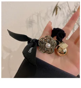 Chouchou de cheveux noir en strass camélia avec ruban et breloque boule dorée femme.