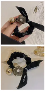 Chouchou noir à camélia en strass avec élégant ruban et perle pour coiffure élégante de femme.