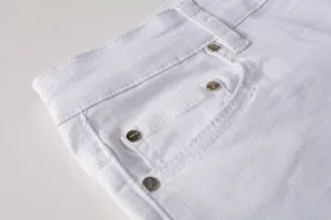 White denim jeans detail shot showcasing premium fabric, metal rivets and neat pocket stitching.