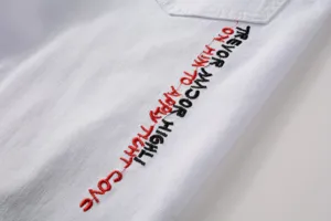 White denim pants fabric detail close up with stylish red and black embroidered text