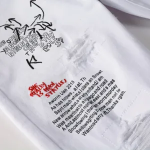 Men's white ripped stretch denim jeans with stylish graffiti embroidery and cool streetwear design.
