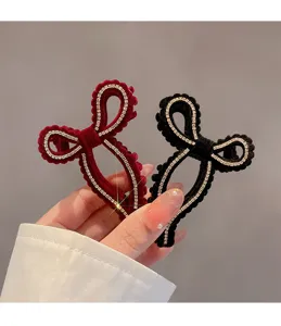 Primo piano sul dettaglio della molletta per capelli con fiocco in velluto e strass brillanti.