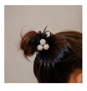Vue rapprochée du chouchou à cheveux en résille noire avec des boules de strass.
