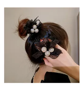 Gros plan sur l'élastique à cheveux en tulle noir et strass avec boule de cristal.