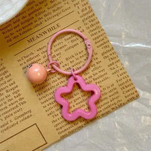 Detailed view of pink star acrylic keychain and bell on vintage newspaper backdrop