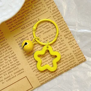 Close-up of bright yellow star-shaped keychain with matching bell on vintage paper
