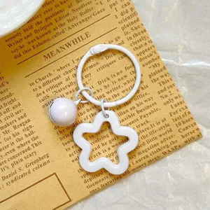 Detailed view of white star-shaped acrylic keychain with matching bell accessory
