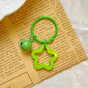 Detail of a vibrant green star acrylic keychain with matching bell on vintage paper.