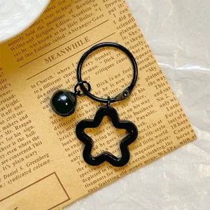 Detailed view of the black star-shaped acrylic pendant with a matching black bell.