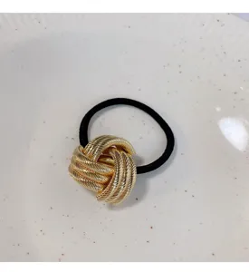 Haarband met gouden metalen knoop en zwarte elastische band, elegant haaraccessoire voor dames.