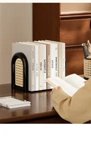Fermalibri moderno nero con inserto in rattan su una scrivania in legno massiccio.