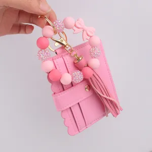 Detalle tarjetero pulsera silicona rosa, cartera cuero llavero borla elegante