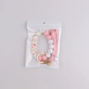 Silicone beaded keychain bracelet with pink leather tassel and gold hardware in clear bag.