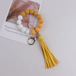 Silicone beaded keychain bracelet with leather tassel, stylish yellow white design.