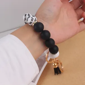 Silicone beaded wristlet keychain with cross print, black and white design with tassel pendant.