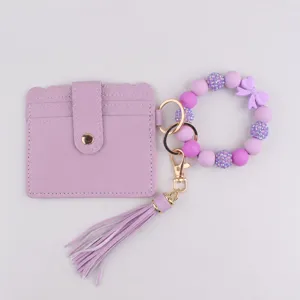 Monedero tarjetero morado con pulsera de cuentas de silicona y bonito colgante.
