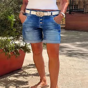 Outdoor lifestyle shot of high-waist women's cuffed denim shorts with white belt accessory