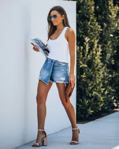 Full body view of a distressed light blue denim skort on a female model outdoors