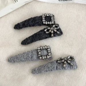 Detailed shot of felt rhinestone hair clips featuring square and bow crystal designs in grey.