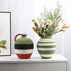 Detail of two hand-painted ceramic vases with colorful horizontal stripes on a white shelf.