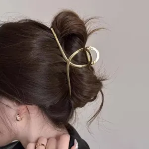 Primo piano dettagliato di un elegante fermacapelli geometrico dorato su uno chignon chic.