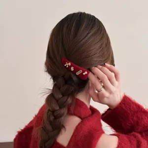 Gedetailleerde opname van een rood fluwelen haarspeld met gouden bedels in gevlochten haar.