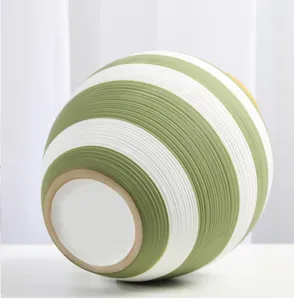 Detailed close-up of a green and white striped ceramic vase showing its ribbed texture and base.